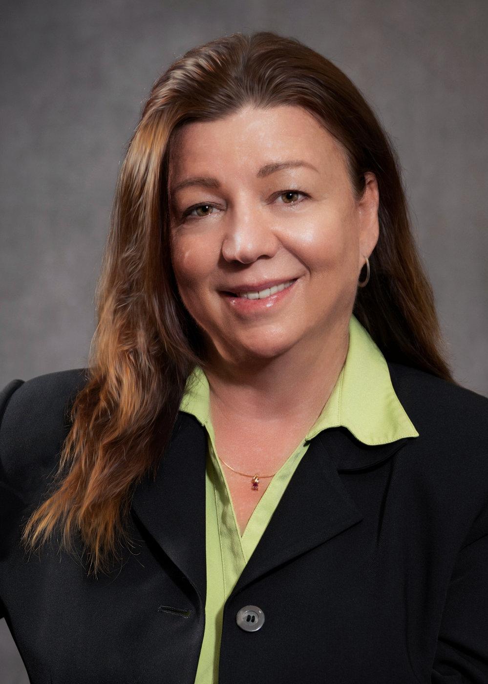 Author Donna Rodrigues, smiling, in a black blazer and green blouse